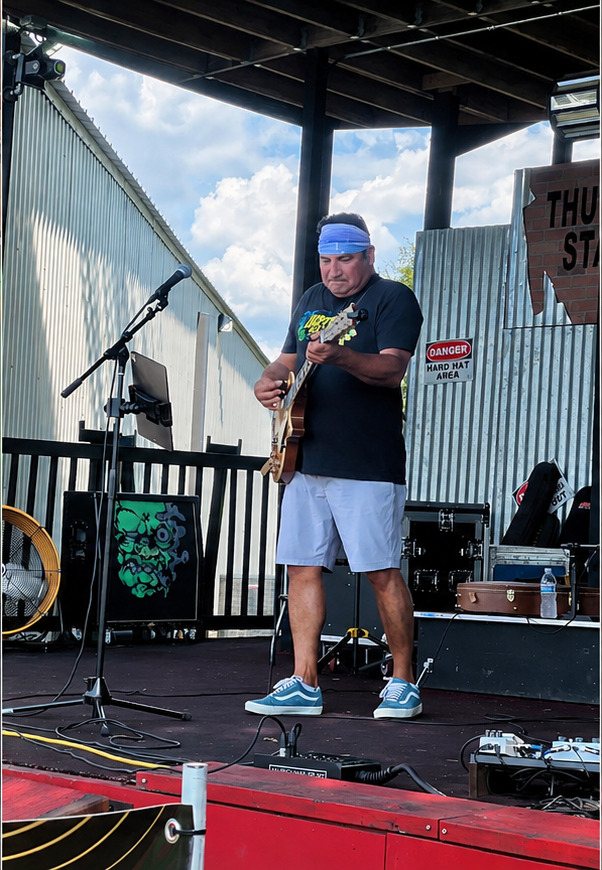 Tom Reyes performing on an outdoor stage
